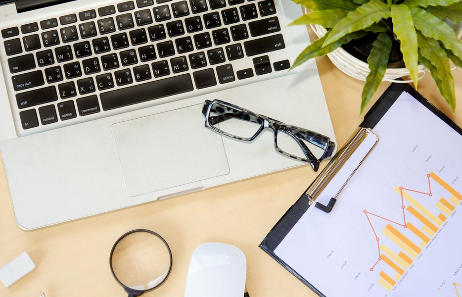 a desk with a laptop and a clipboard