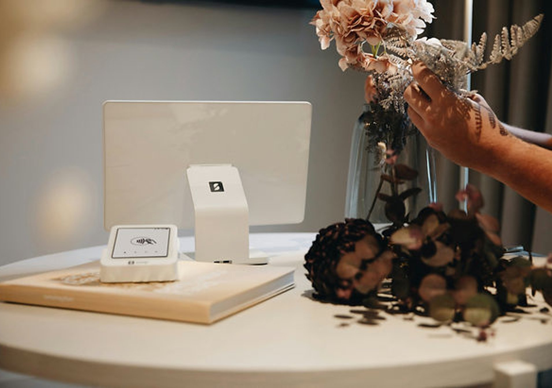 an arrangement of flowers on a table with a book